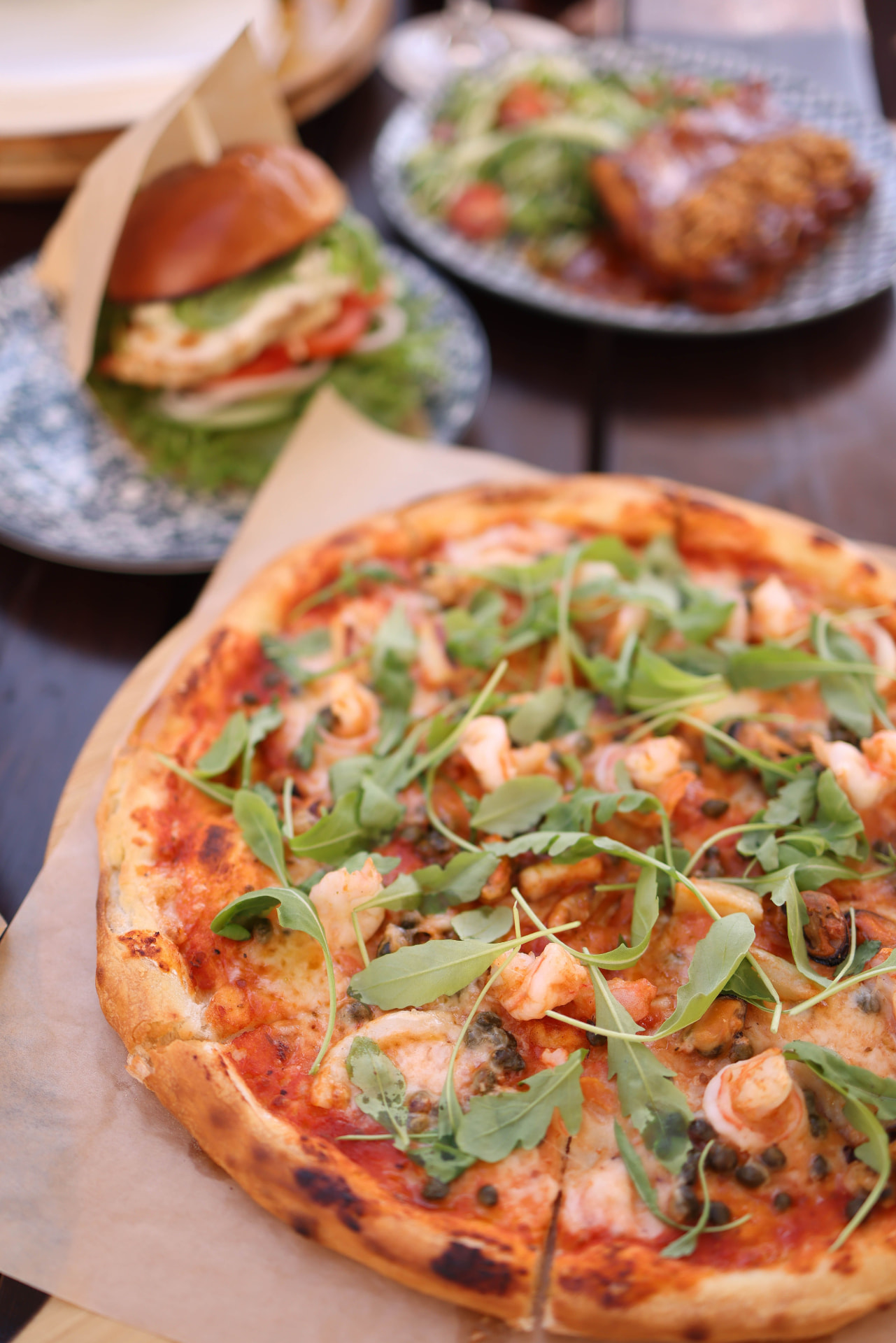 Knapperige pizza met gamba's, rucola, kappertjes en gesmolten kaas, geserveerd op bakpapier